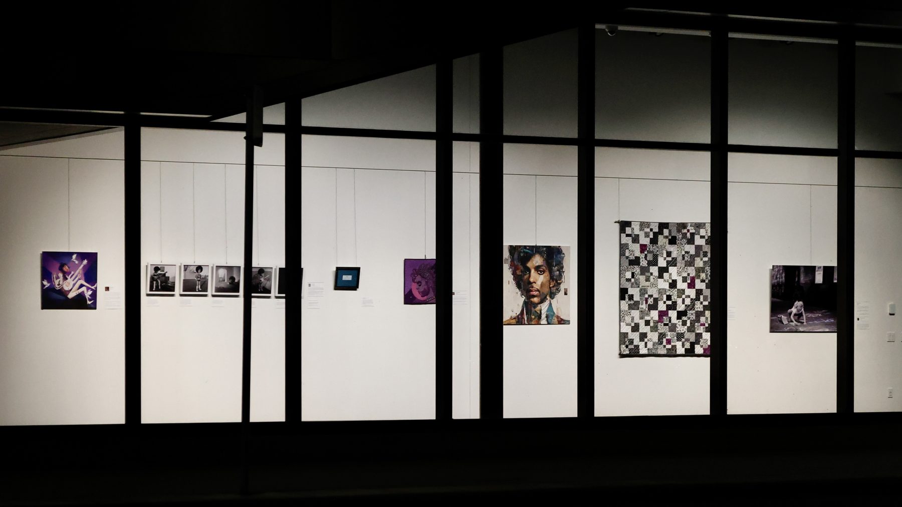 The Capri Theater gallery at night, artworks lit behind a wall of windows